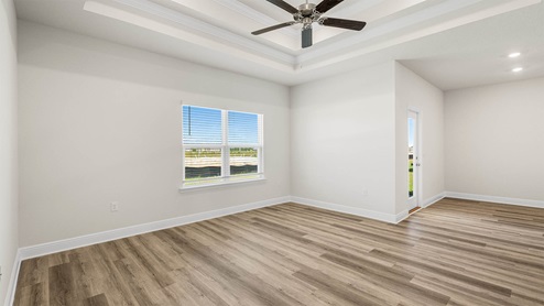 Open living room with tray ceilings and ceiling fan and EVP flooring and window and dining area.