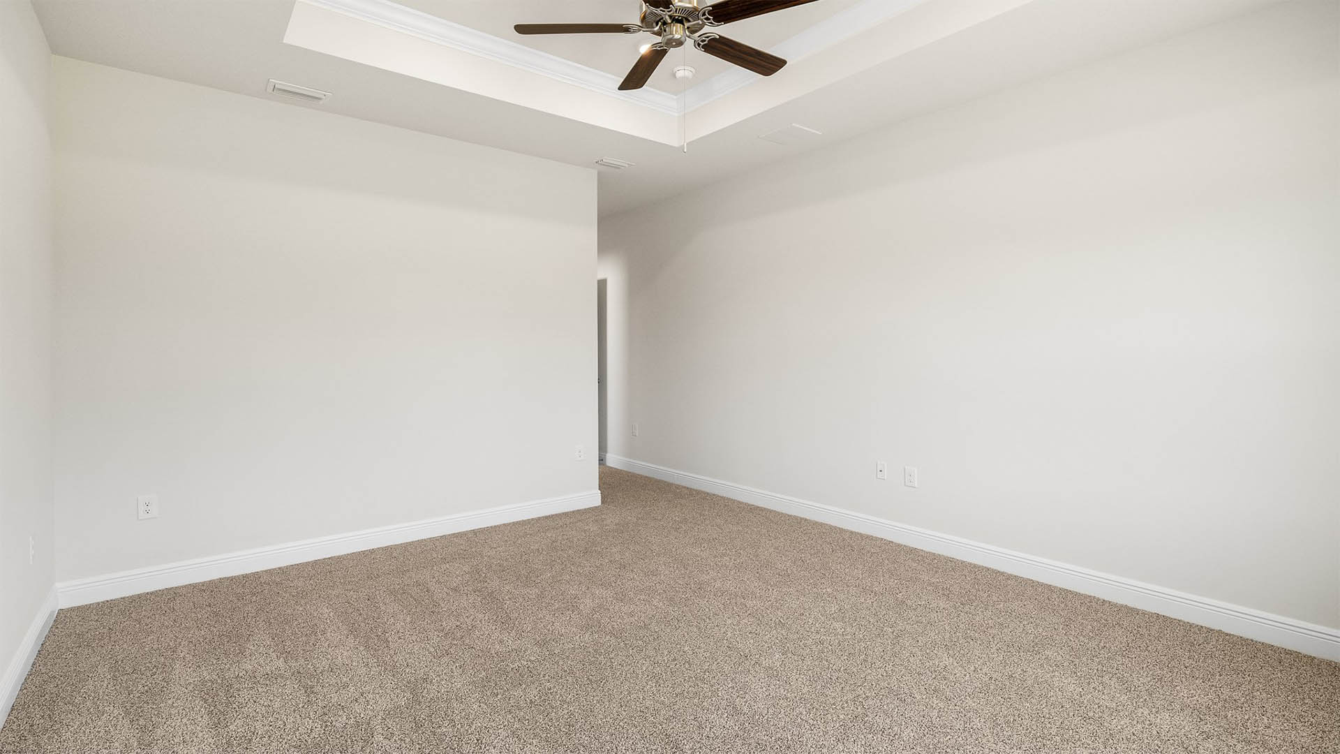 Primary bedroom with carpet floors and tray ceilings and ceiling fan.