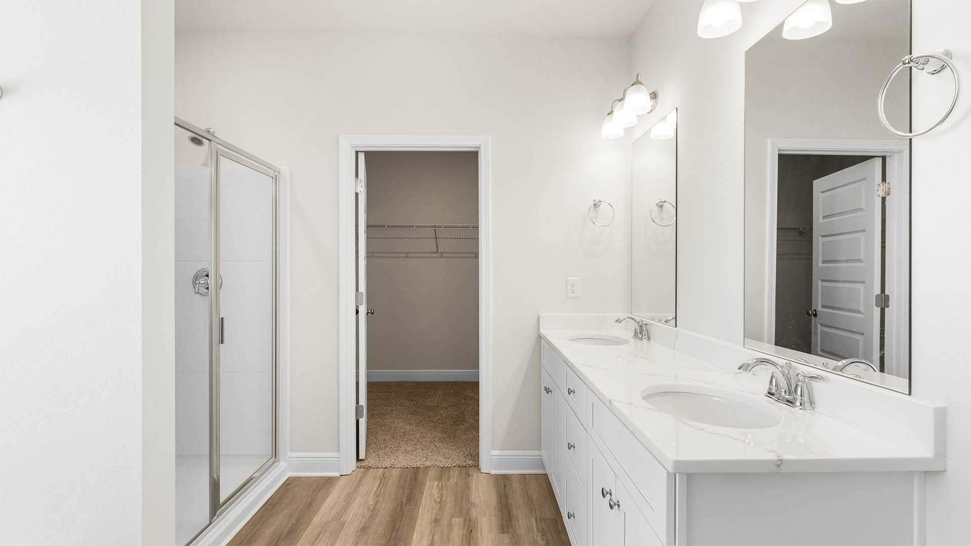 Primary bathroom with double vanity quartz countertops and shower and closet entrance.