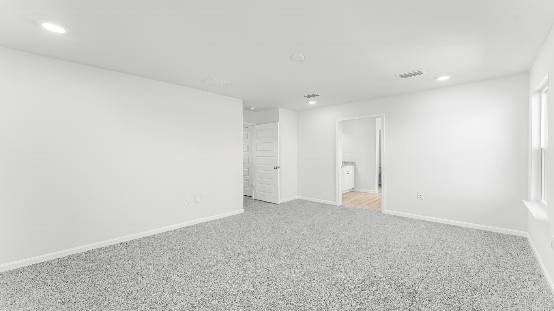 Primary bedroom with carpet floor and bathroom entrance.