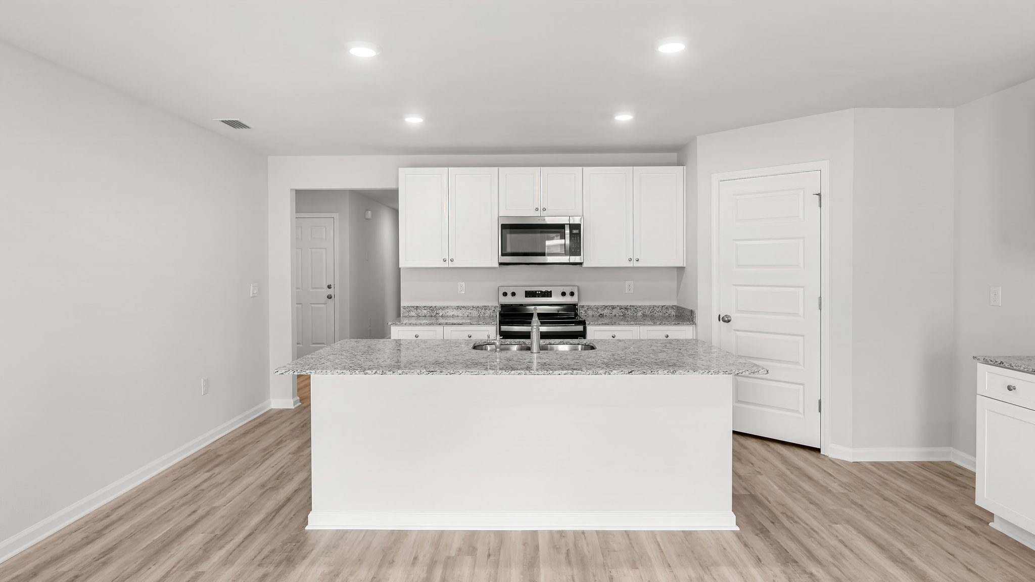 Kitchen with island and white cabinets and stainless-steel appliances and granite countertops and pantry.