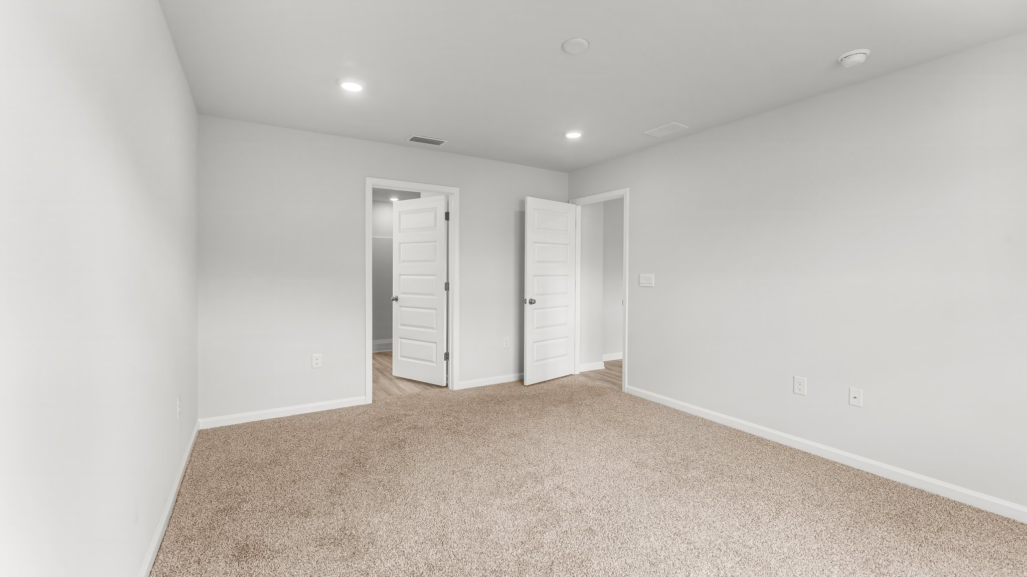 Primary bedroom with carpet flooring and primary bathroom entrance.