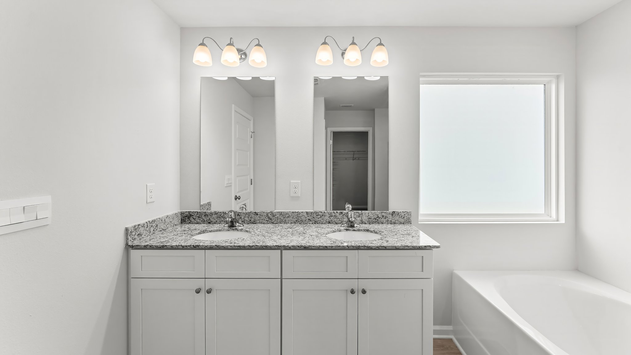 Primary bathroom with double vanity granite countertops and separate tub and shower and EVP flooring.