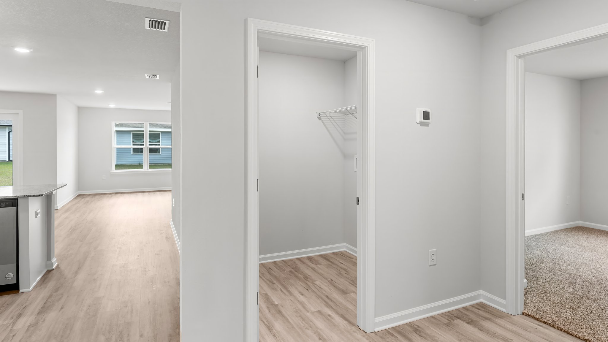 Hallway by garage entrance and bedroom and laundry room with EVP flooring.