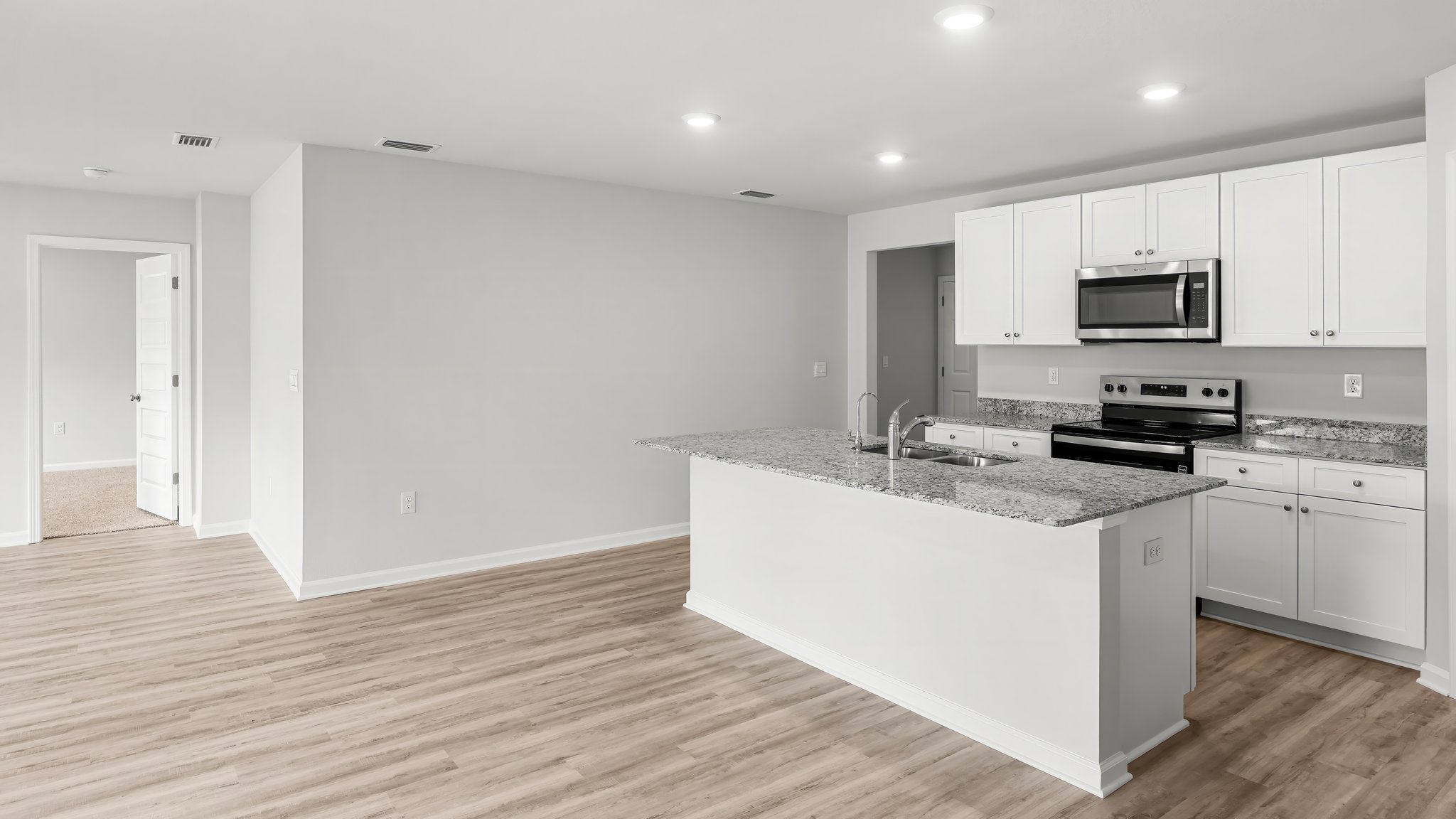 Kitchen island with white cabinets and stainless-steel appliances and granite countertops.