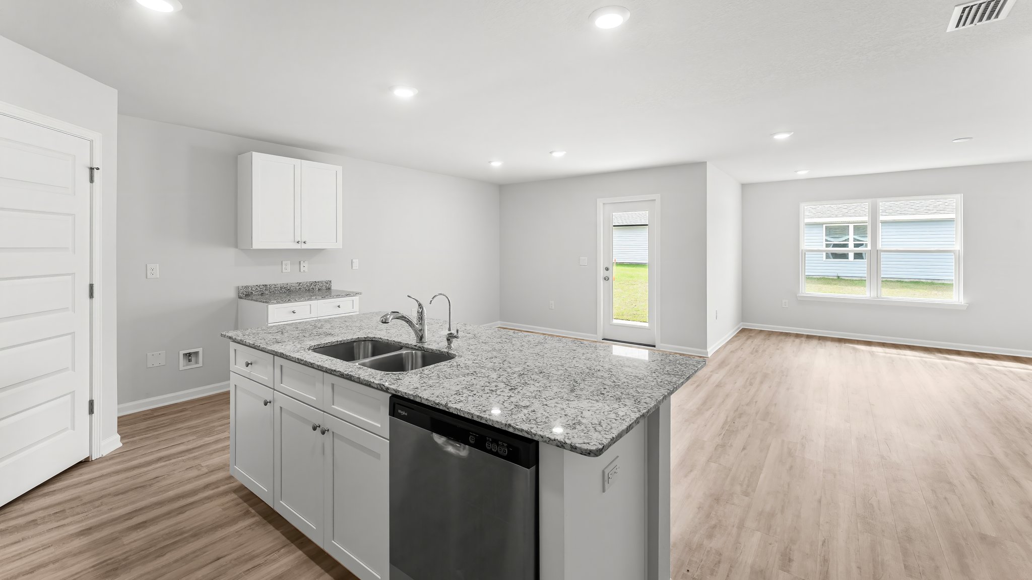 Kitchen island with white cabinets and stainless-steel appliances and granite countertops.