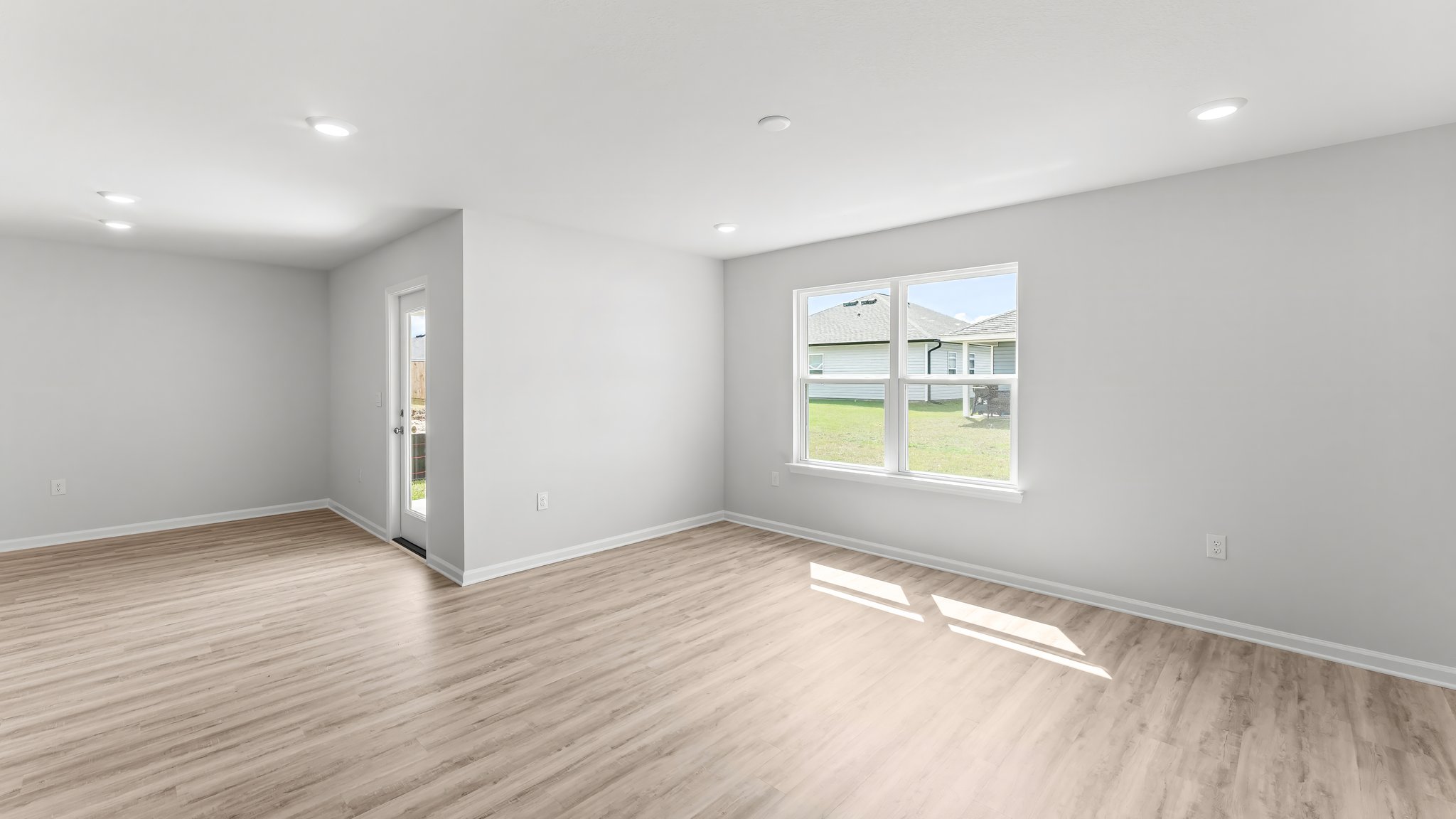 Open living room and dining area with EVP flooring and two windows and back door.