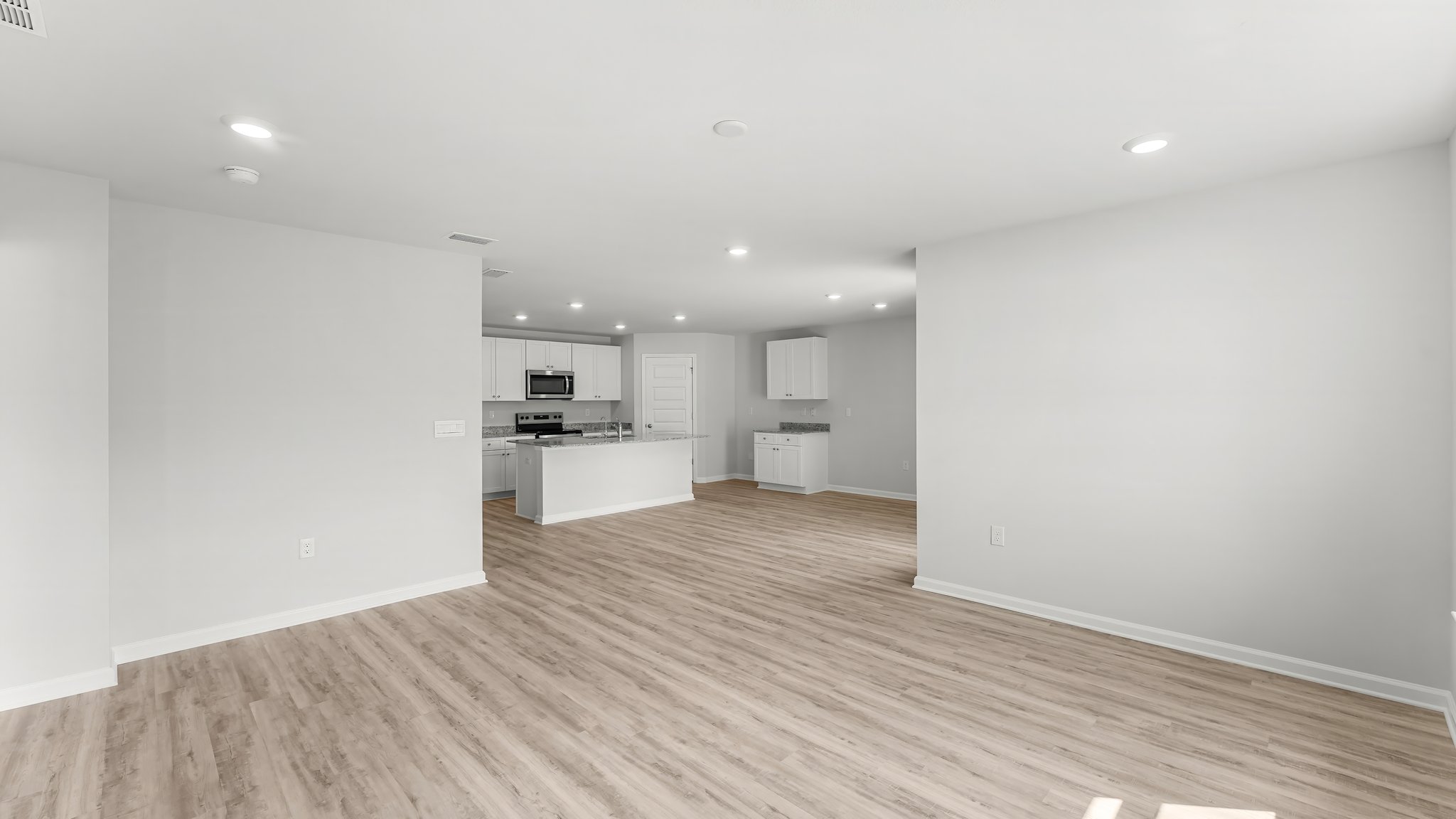 Open living room with EVP flooring looking into kitchen.