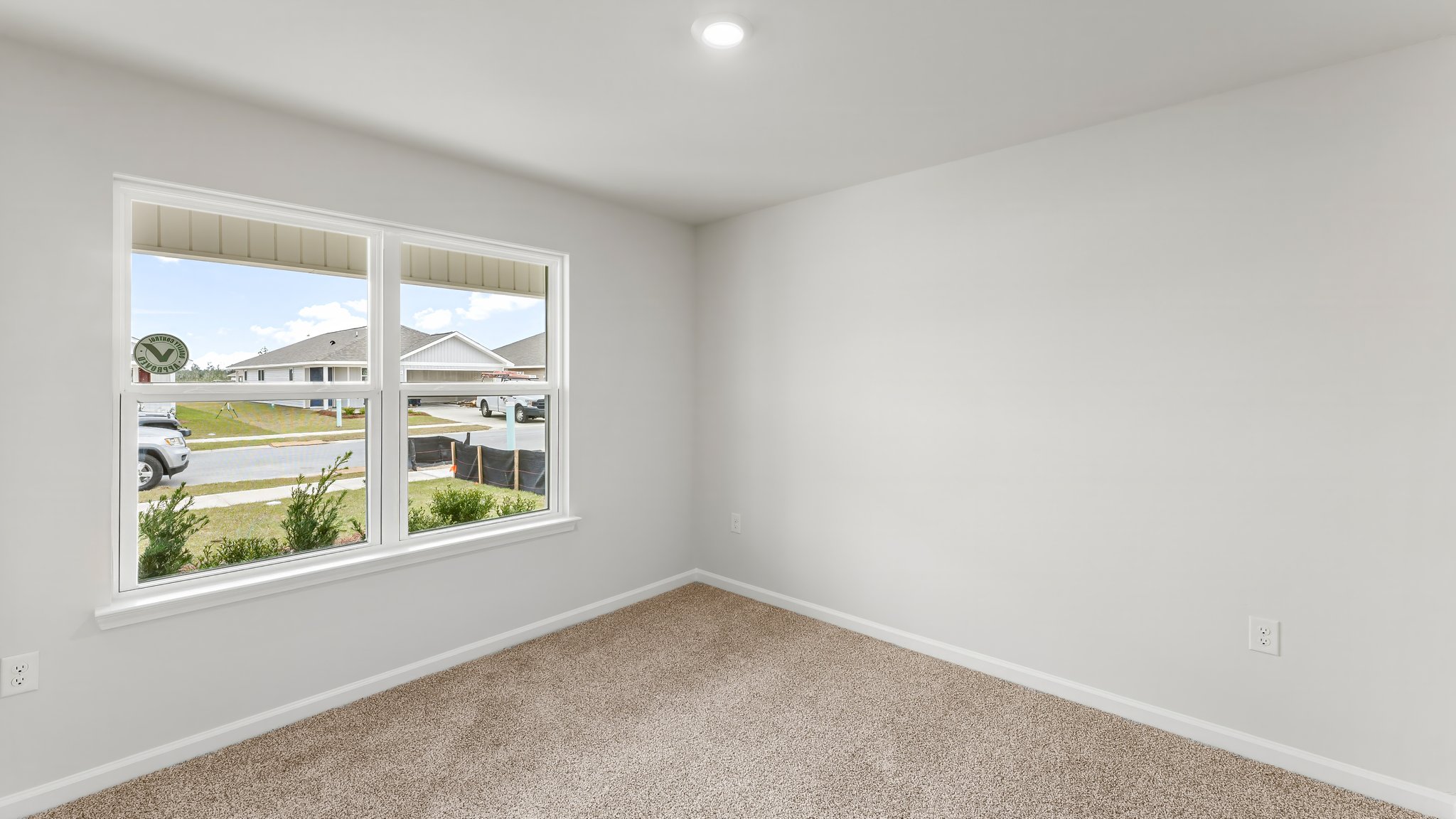 Bedroom with carpet flooring and two windows.