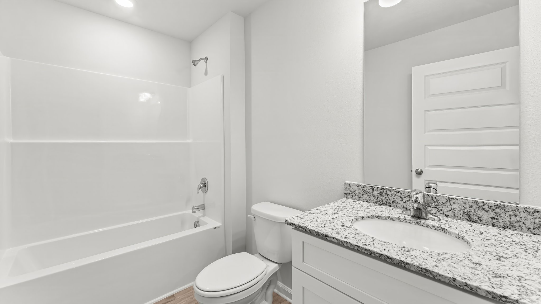 Bathroom with EVP flooring and single vanity granite countertops and toilet and tub and shower.