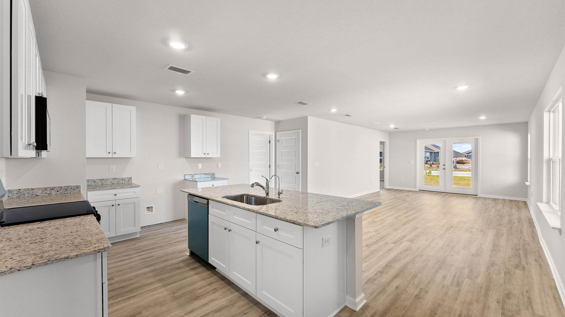 Open kitchen and living room with kitchen island with granite countertops and stainless-steel appliances.