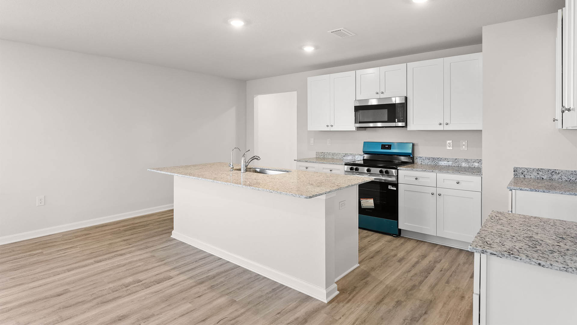 Kitchen with island with granite countertops and stainless-steel appliances and white cabinets.