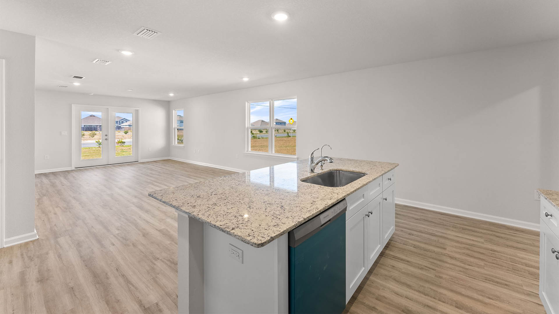 Kitchen with island with granite countertops and stainless-steel appliances and white cabinets.