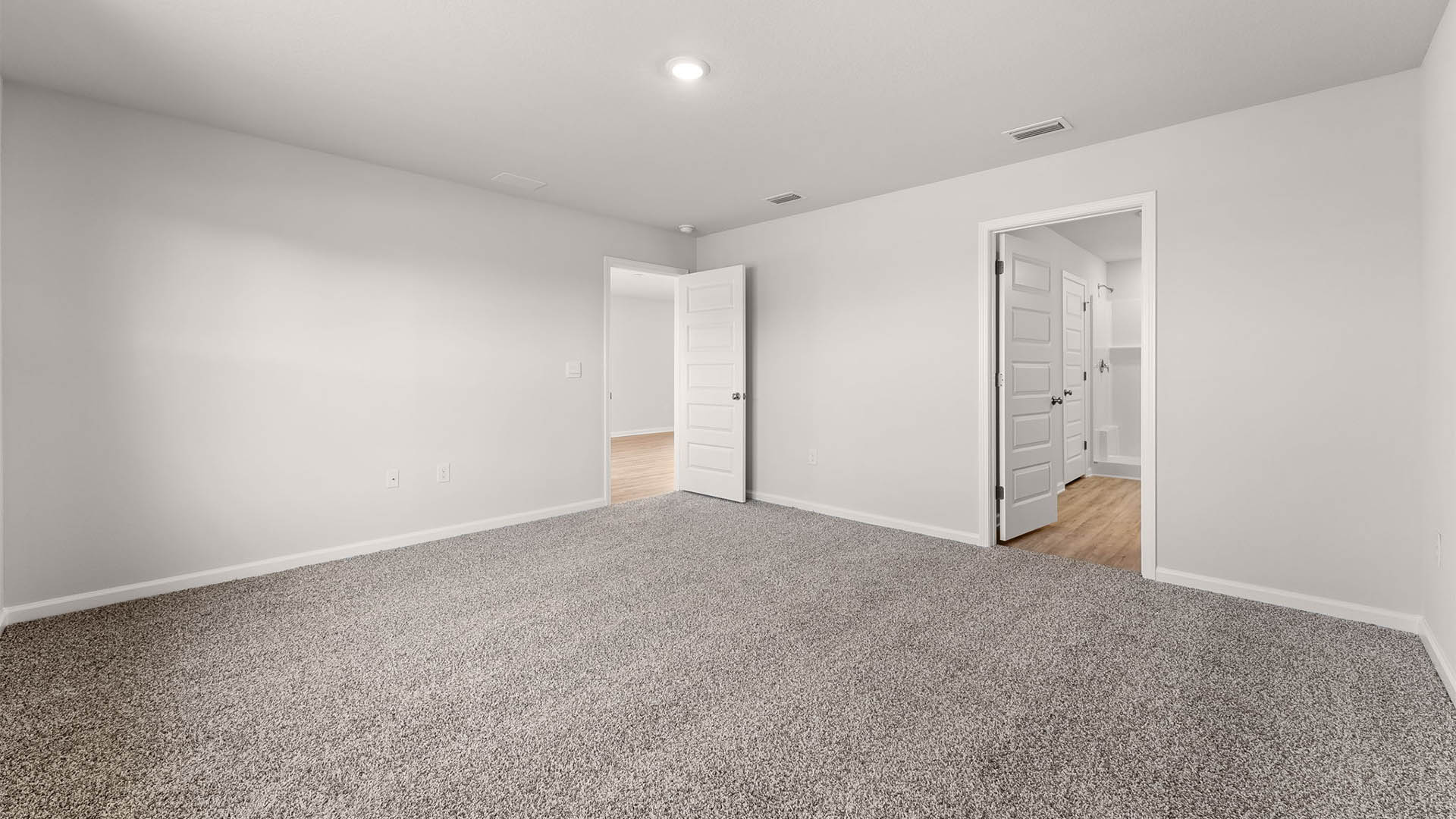 Primary bedroom with carpet floors and primary bathroom entrance.