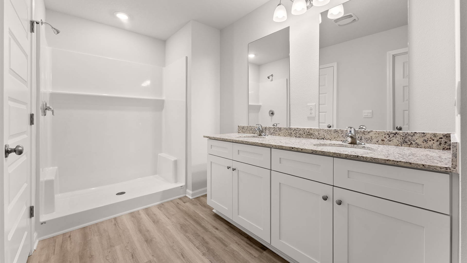 Primary bathroom with double vanity granite countertops and shower and closet.