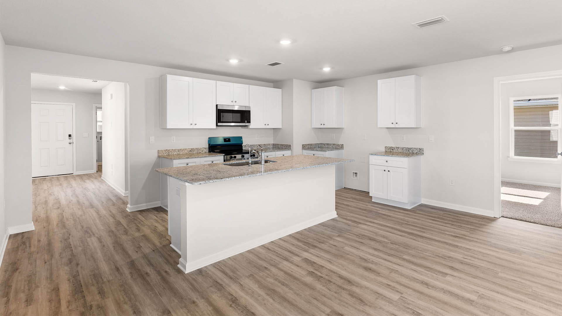 Kitchen with island with granite countertops and stainless-steel appliances and white cabinets.
