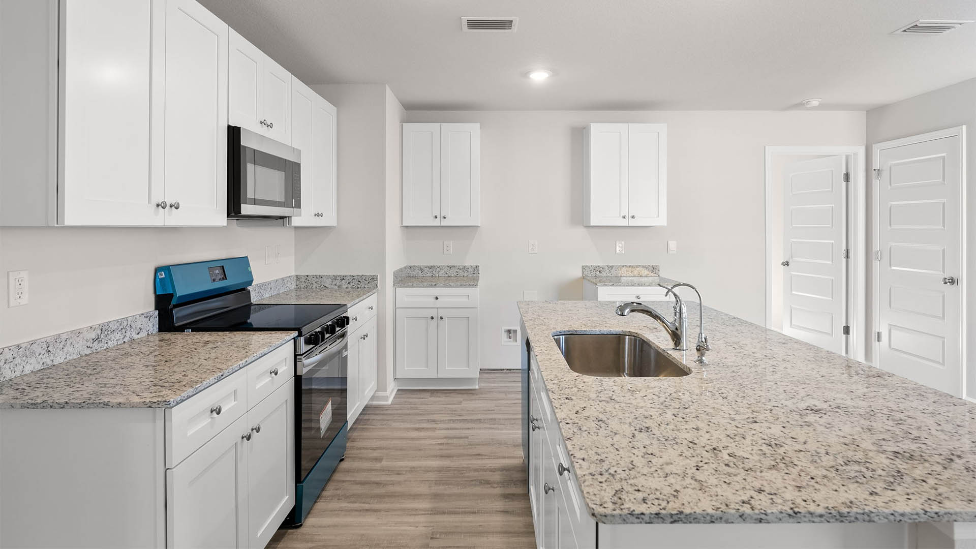Kitchen with island with granite countertops and stainless-steel appliances and white cabinets.