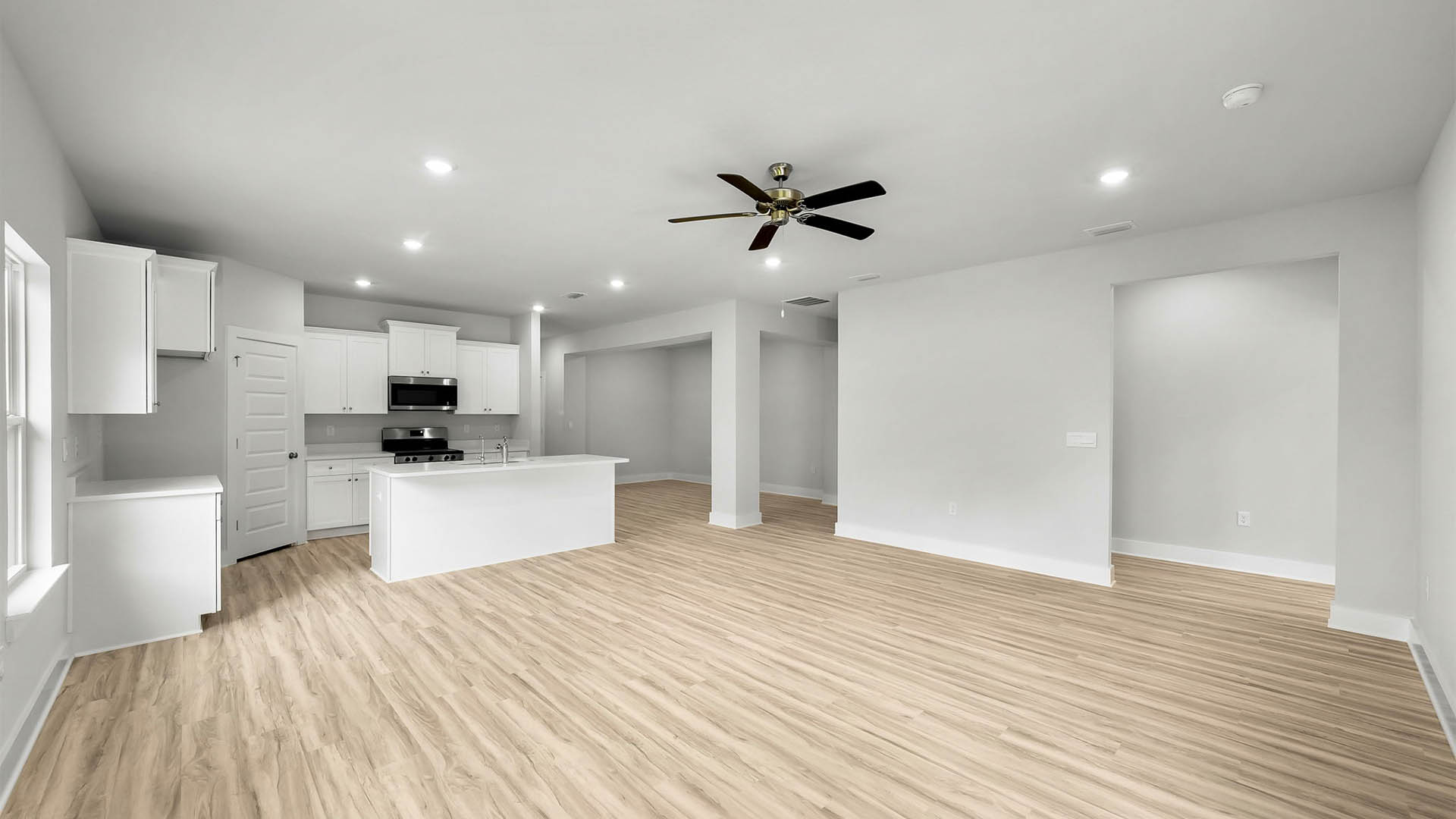 Open Living room with EVP flooring and ceiling fan and kitchen.