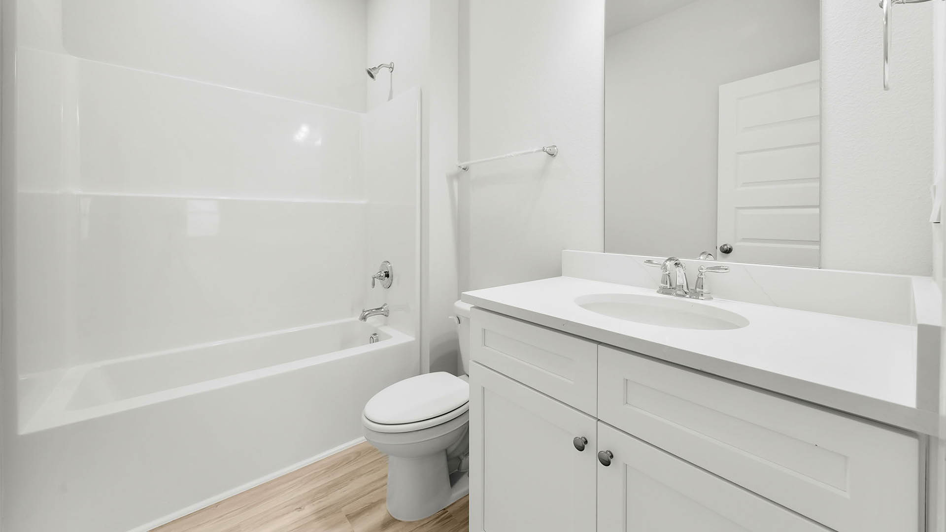 Bathroom with EVP flooring and quartz countertops and single vanity and white cabinets and tub and shower.
