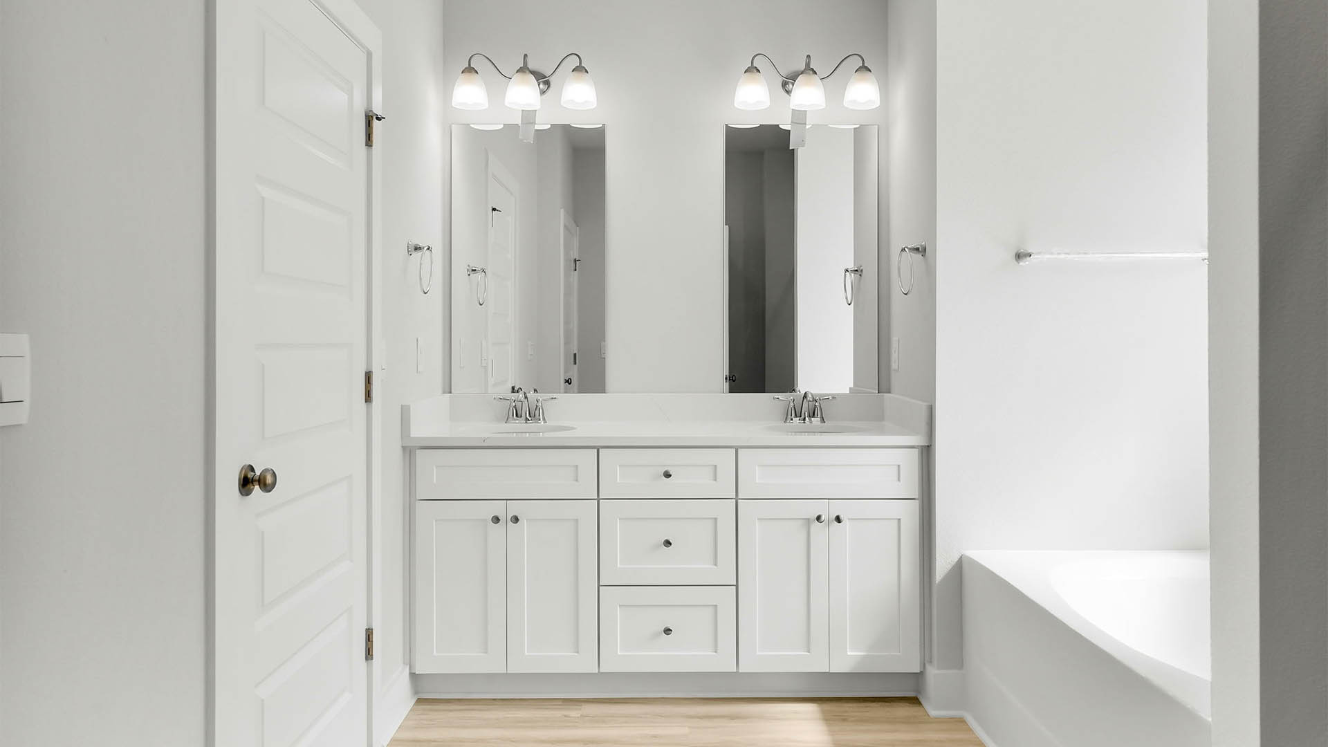 Primary bathroom with double vanity granite countertops and EVP flooring and white cabinets and walk-in closet.