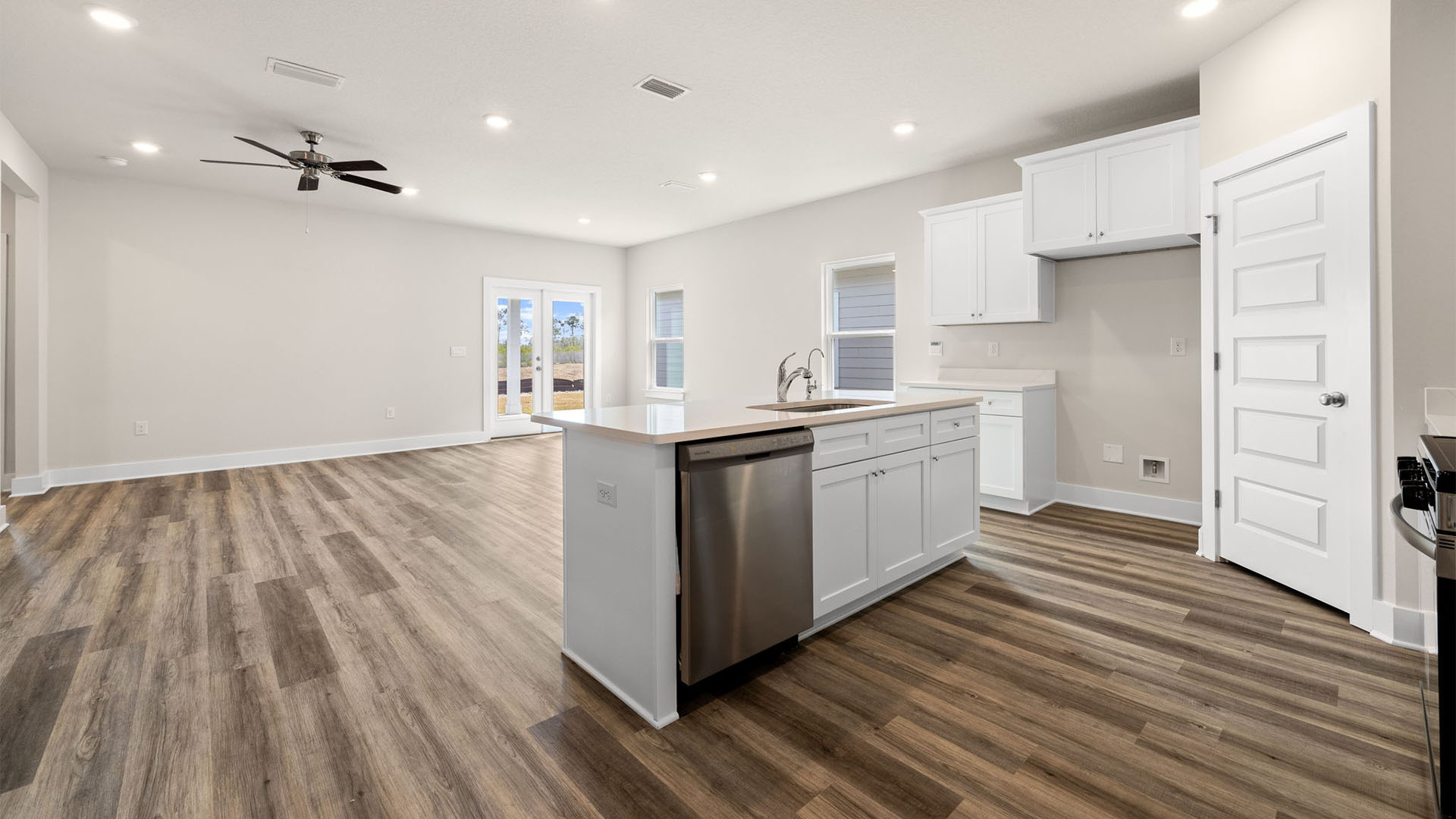 Kitchen with quartz countertops and white cabinetry and island and stainless-steel appliances and pantry.