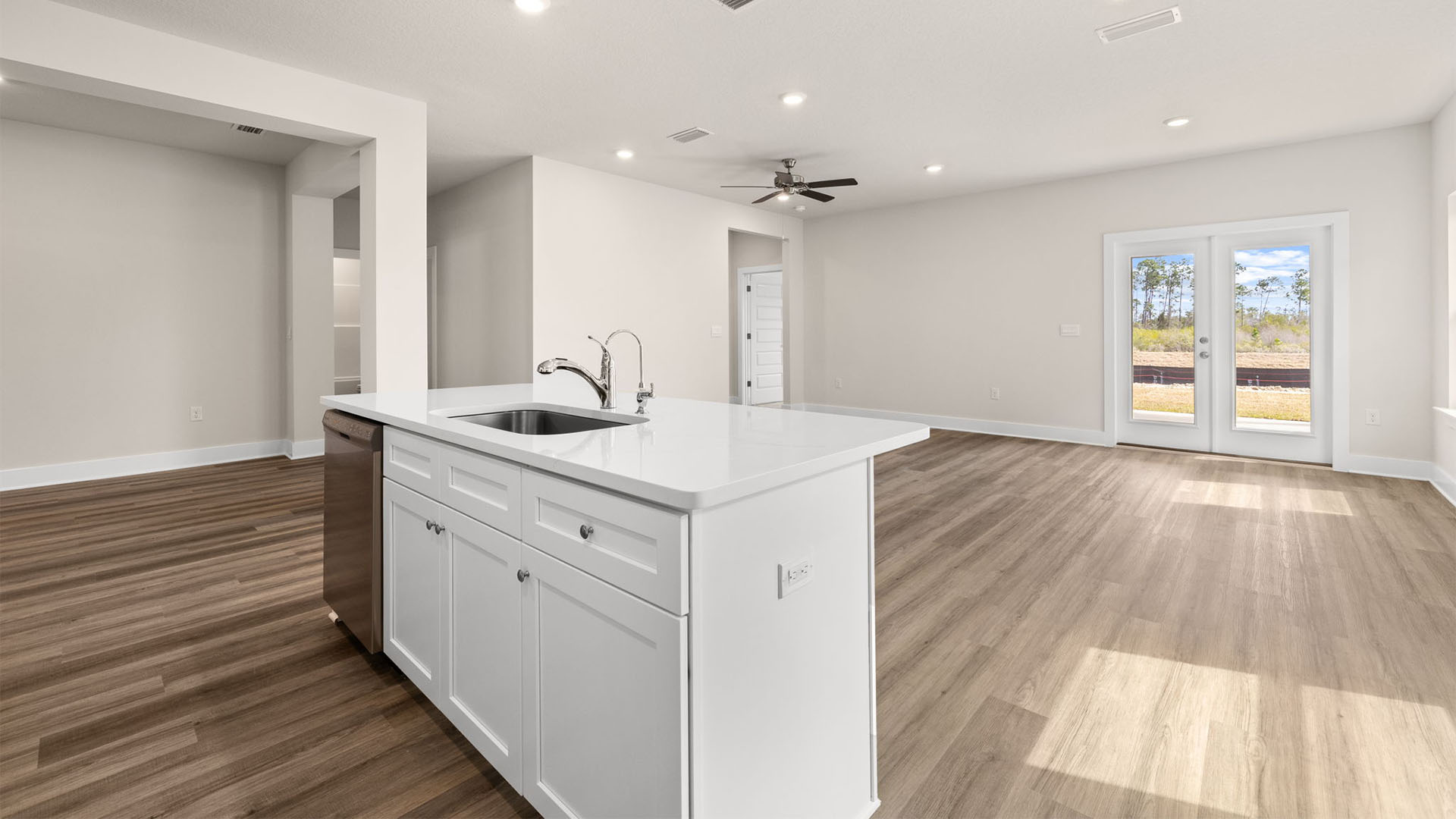 Kitchen island with dishwasher and quartz countertops and living room view.