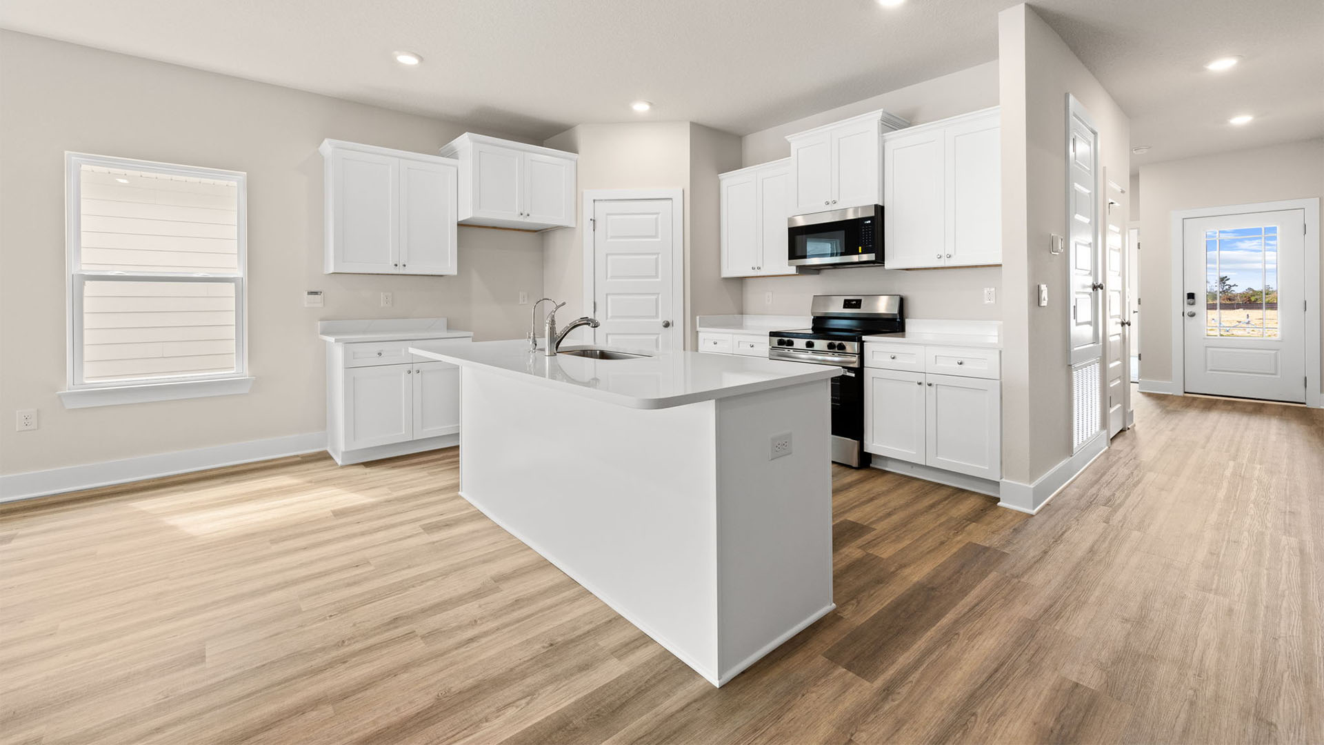 Kitchen with quartz countertops and white cabinetry and island and stainless-steel appliances and pantry.