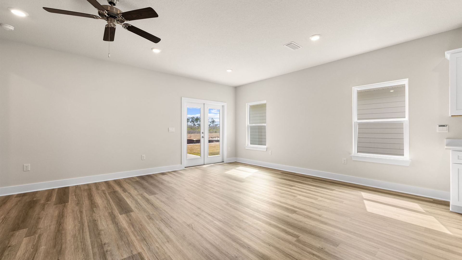 Open Living room with EVP flooring and ceiling fan and windows and back door.