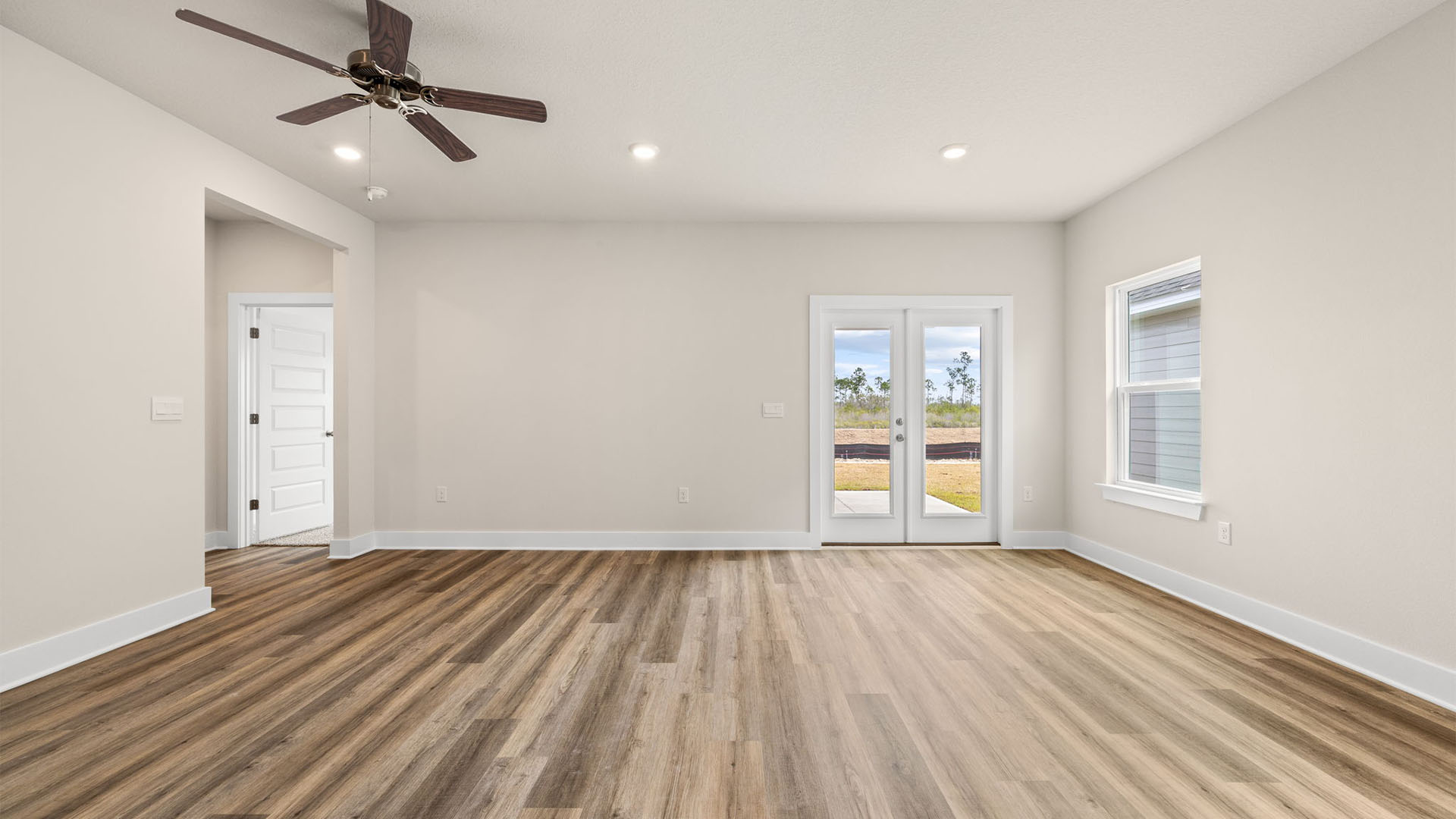 Open Living room with EVP flooring and ceiling fan and windows and back door.