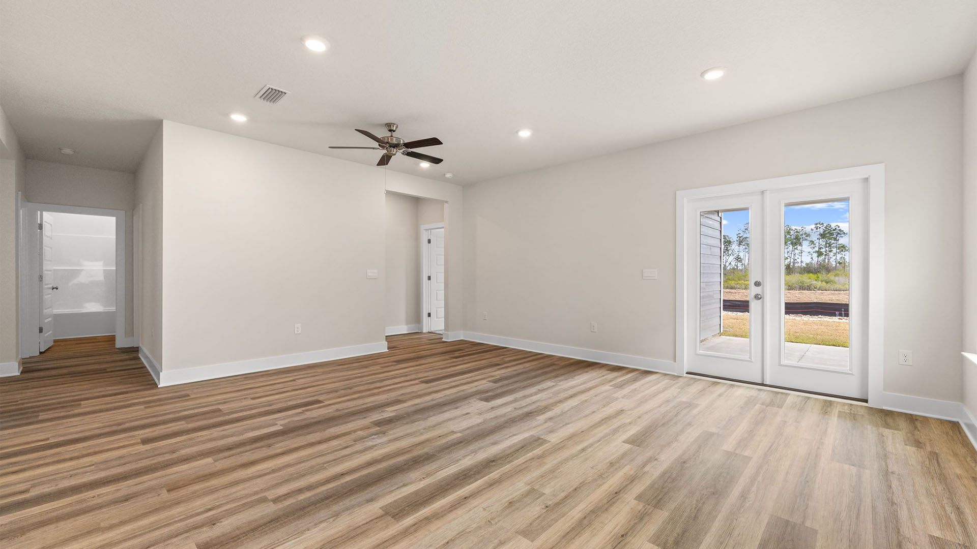 Open Living room with EVP flooring and ceiling fan and windows and back door.