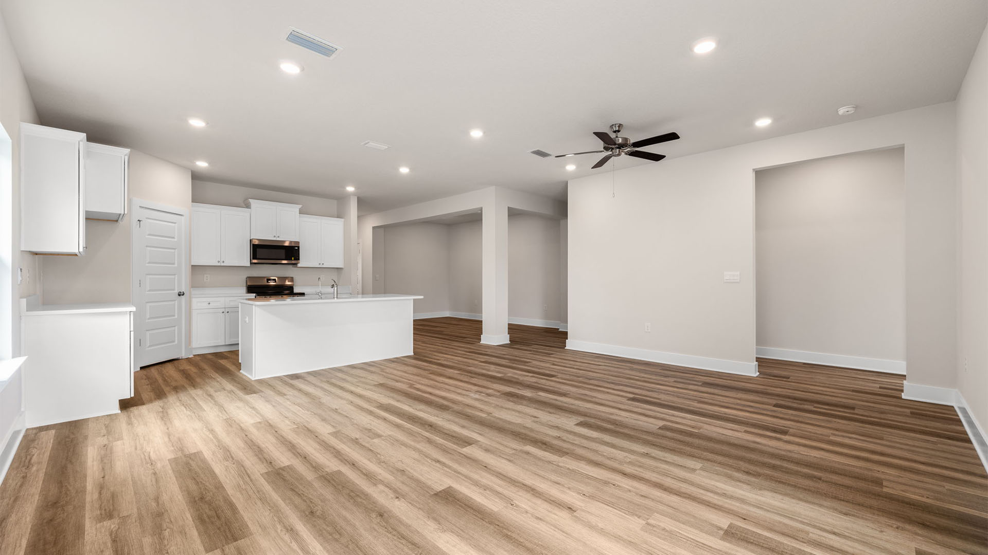 Open Living room with EVP flooring and ceiling fan and kitchen.