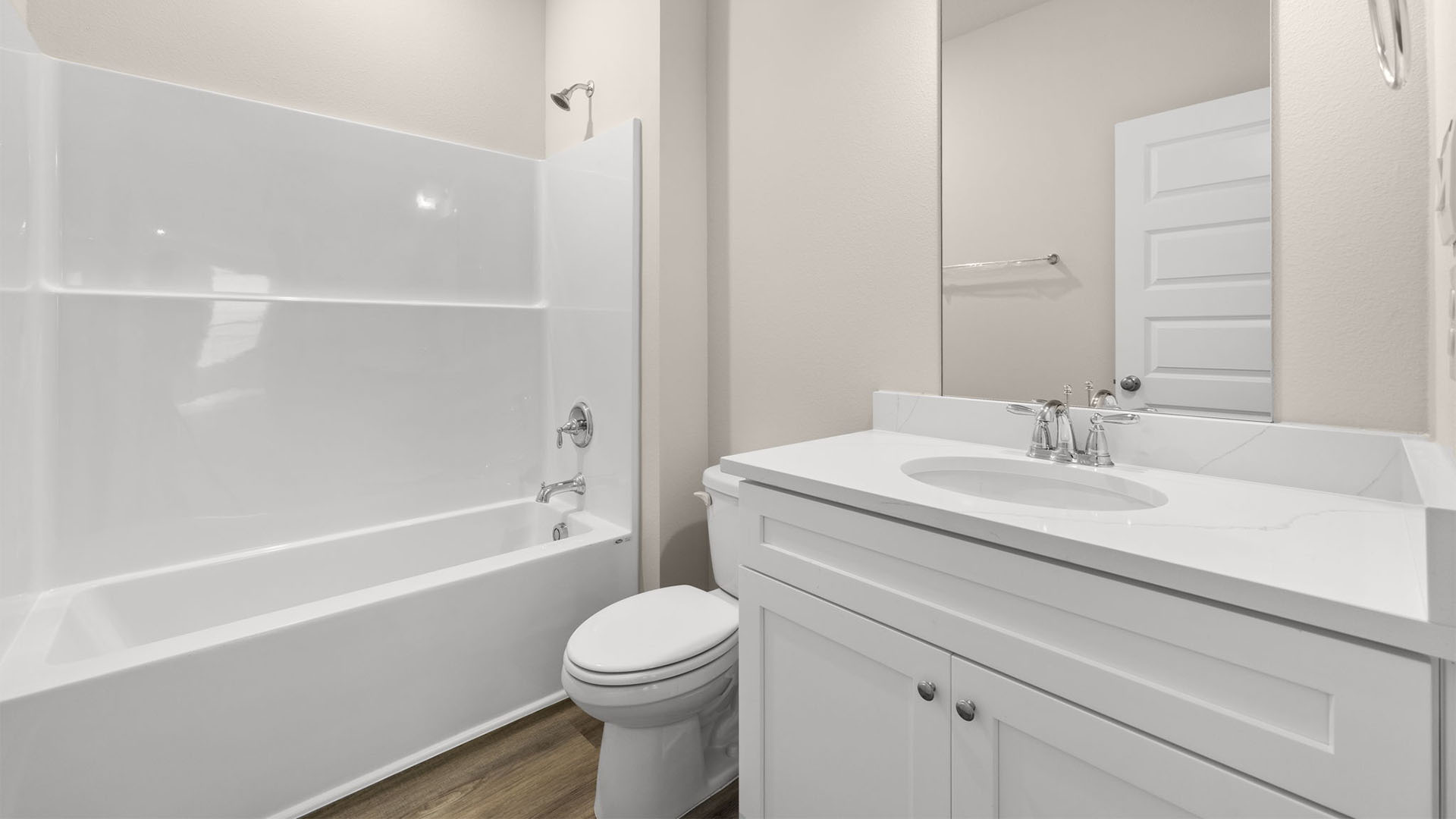 Bathroom with EVP flooring and quartz countertops and single vanity and white cabinets and tub and shower.