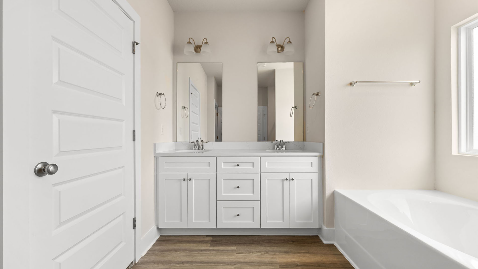 Primary bathroom with double vanity granite countertops and EVP flooring and white cabinets and walk-in closet.