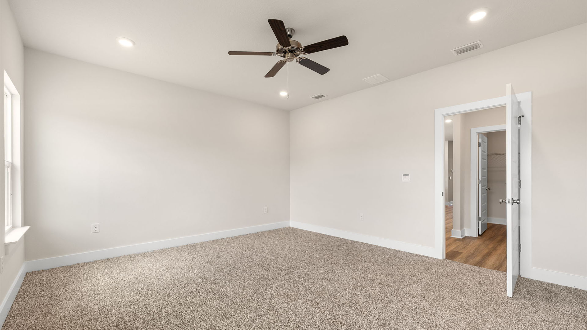 Primary bedroom with carpet flooring and ceiling fan and window.