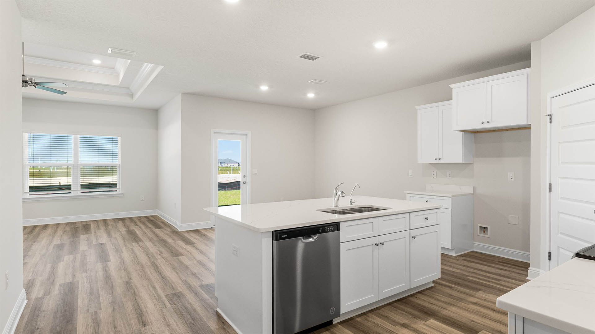 Kitchen with island and quartz countertops and white cabinets and stainless-steel appliances.