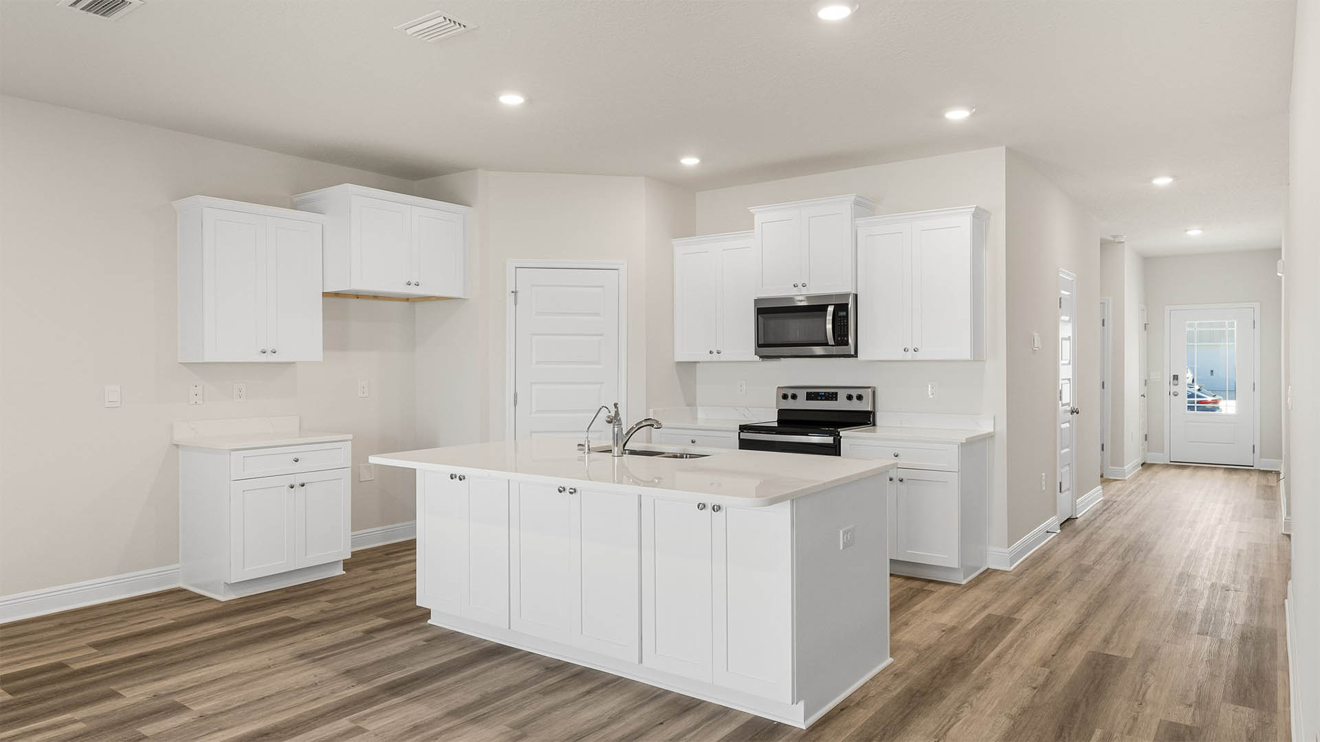 Kitchen with island and quartz countertops and white cabinets and stainless-steel appliances.