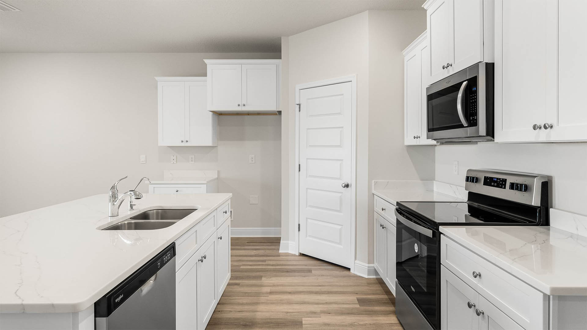 Kitchen with island and quartz countertops and white cabinets and stainless-steel appliances.