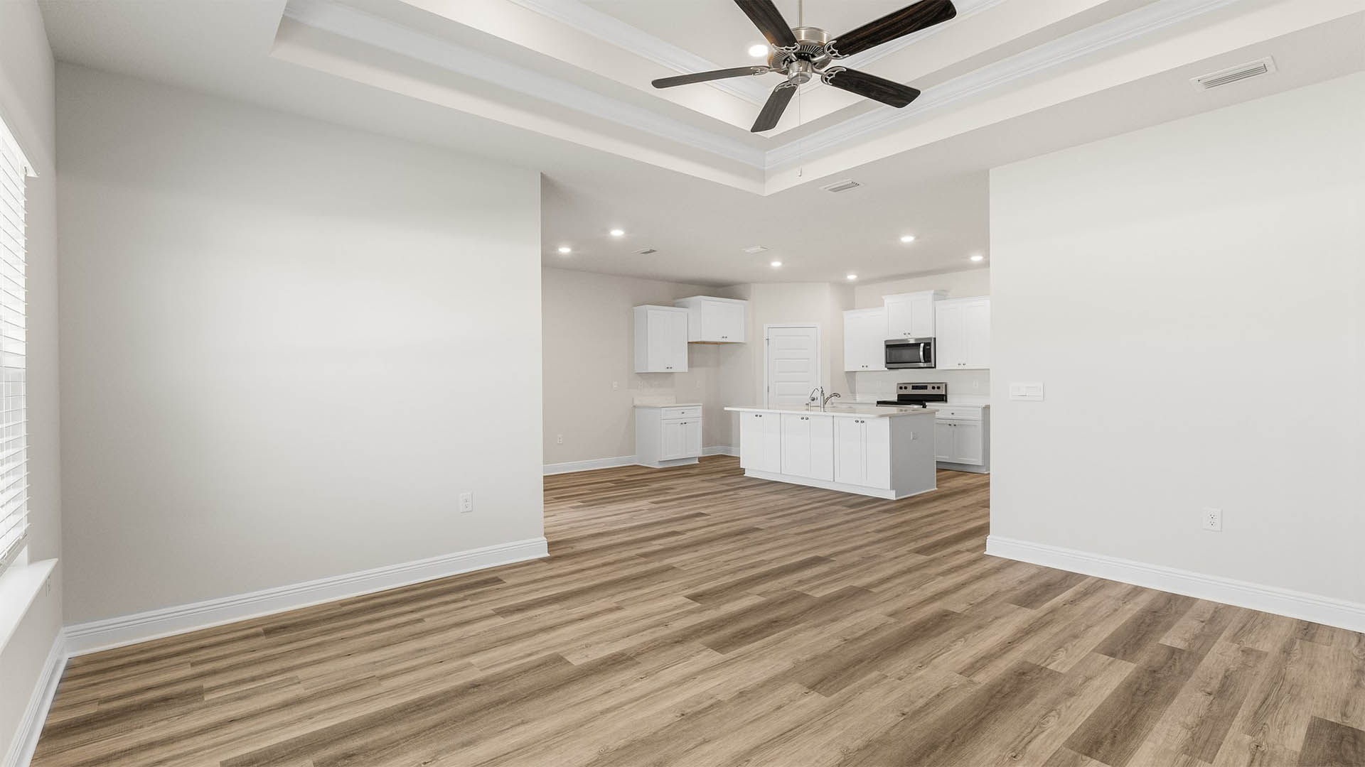 Open living room with tray ceilings and ceiling fan and EVP flooring and kitchen and dining area.