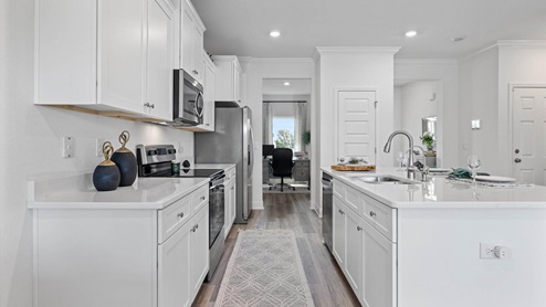 Kitchen with EVP flooring and quartz countertops and white cabinets and Island and stainless-steel appliances.