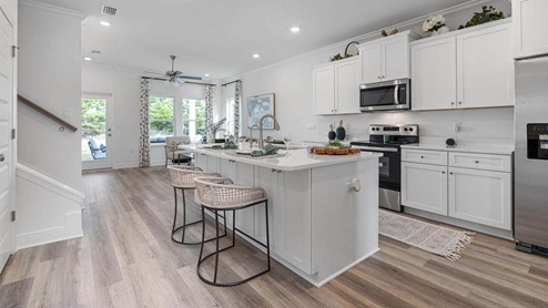 Kitchen with EVP flooring and quartz countertops and white cabinets and Island and stainless-steel appliances.