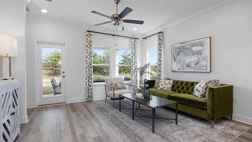 Living room with ceiling fan and EVP flooring and back door.