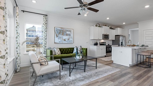 Living room with ceiling fan and EVP flooring and kitchen.