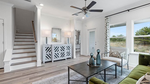 Living room with ceiling fan and EVP flooring and back door and stairs.