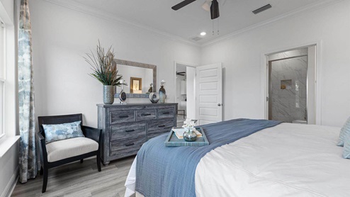 Primary bedroom with EVP flooring with ceiling fan and window and bathroom entrance.