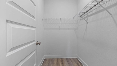 Primary bathroom walk in closet with EVP flooring and ventilated shelving.