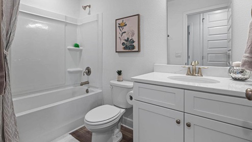 Bathroom with single vanity quartz countertops and white cabinets and toilet and shower.