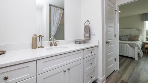 Bathroom with single vanity quartz countertops and white cabinets.
