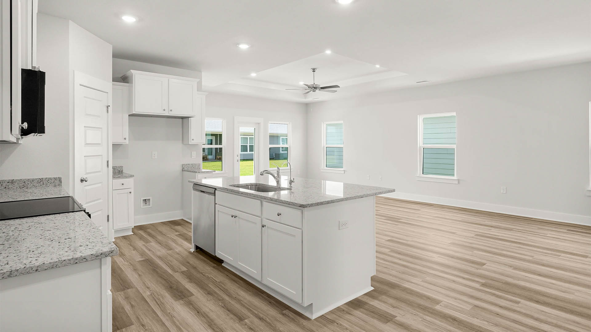 Open kitchen with island and granite countertops and white cabinets and stainless steel appliances and pantry.