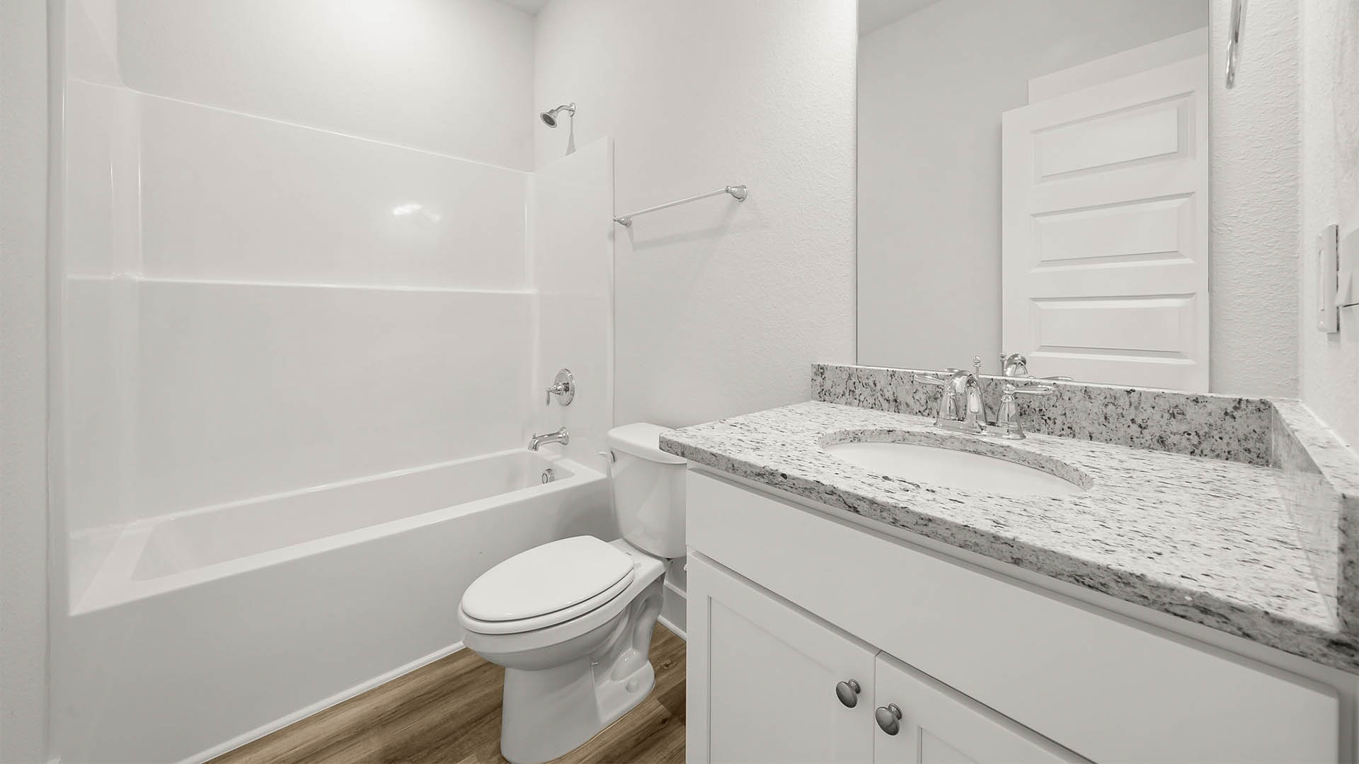 Bathroom with granite countertops and single vanity and white cabinets and EVP flooring and toilet and shower.
