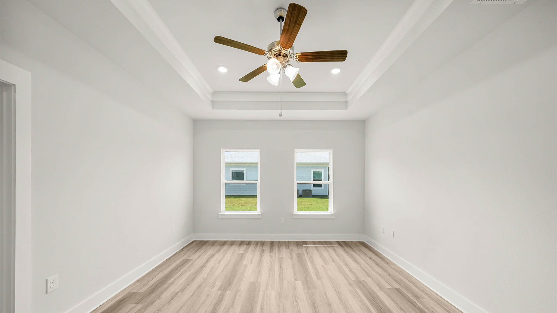 Primary bedroom with EVP flooring and windows and ceiling fan.
